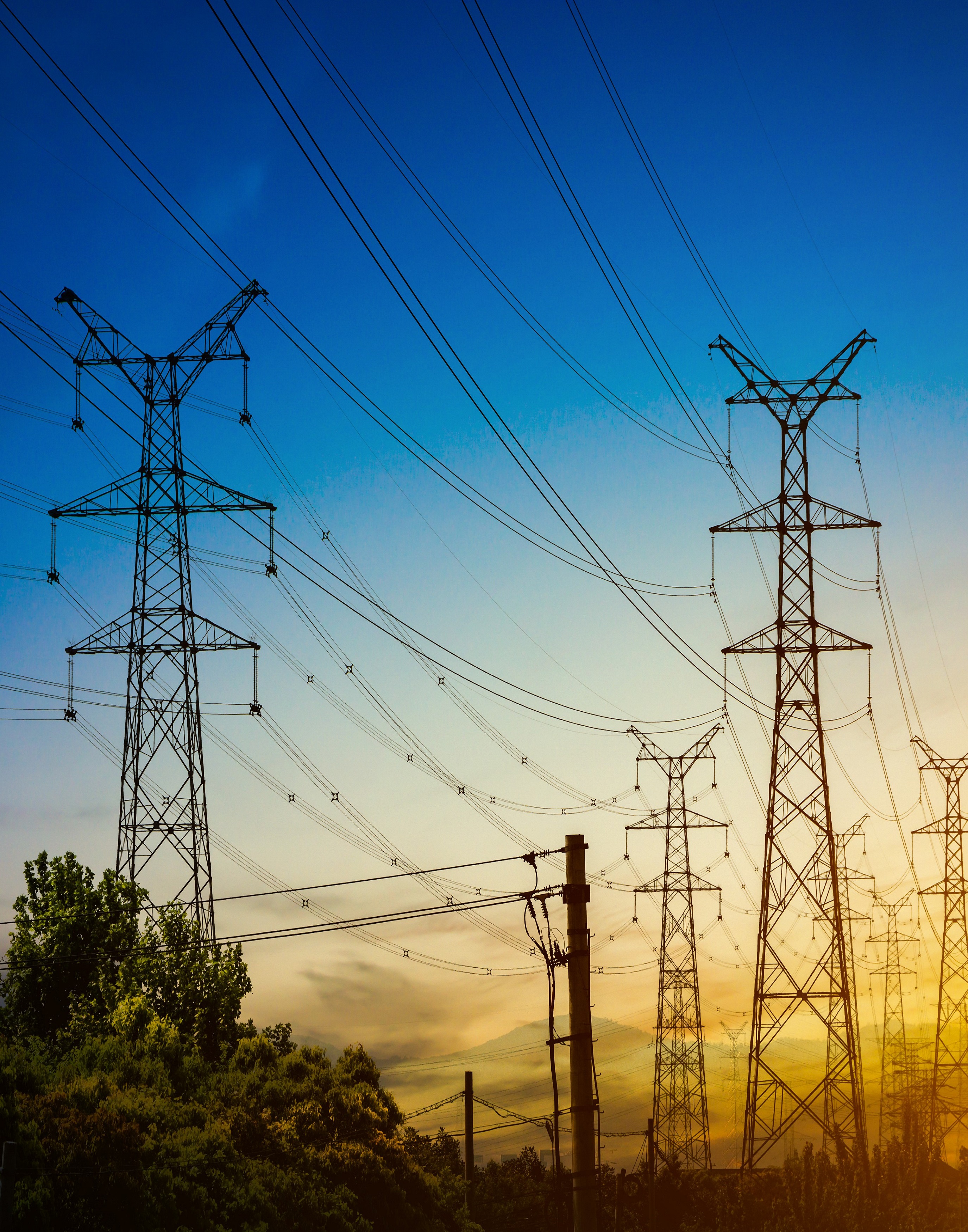 Sun setting behind the silhouette of electricity pylons